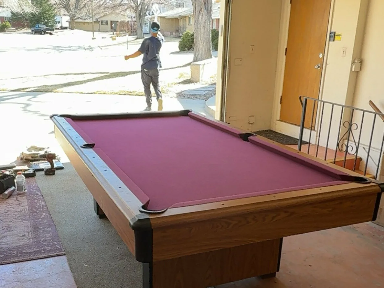 Crew member walking away from a pool table in a garage